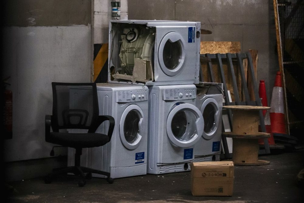 Discarded front-loading washing machines stacked up for removal